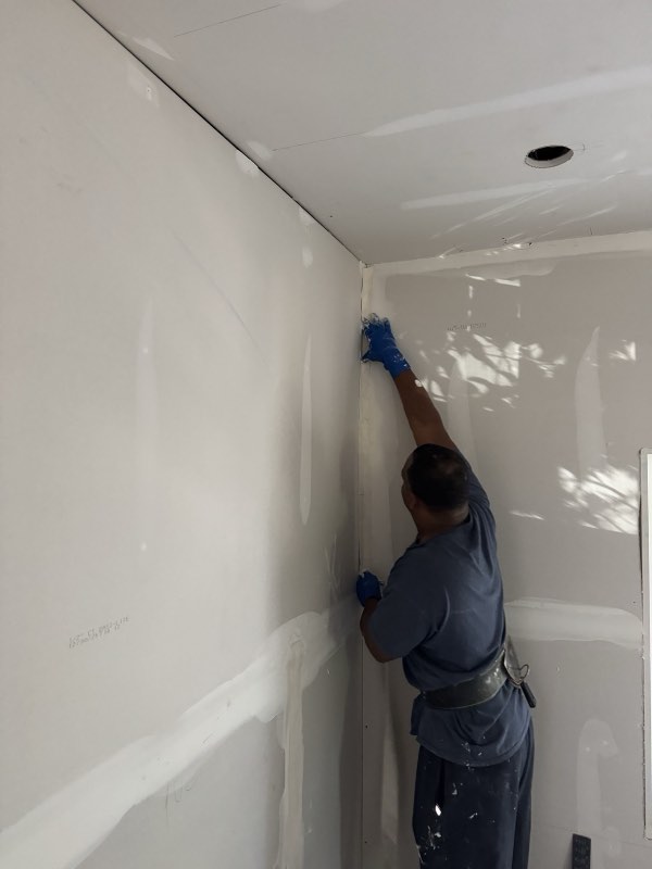 Gary taping an inside corner near the ceiling