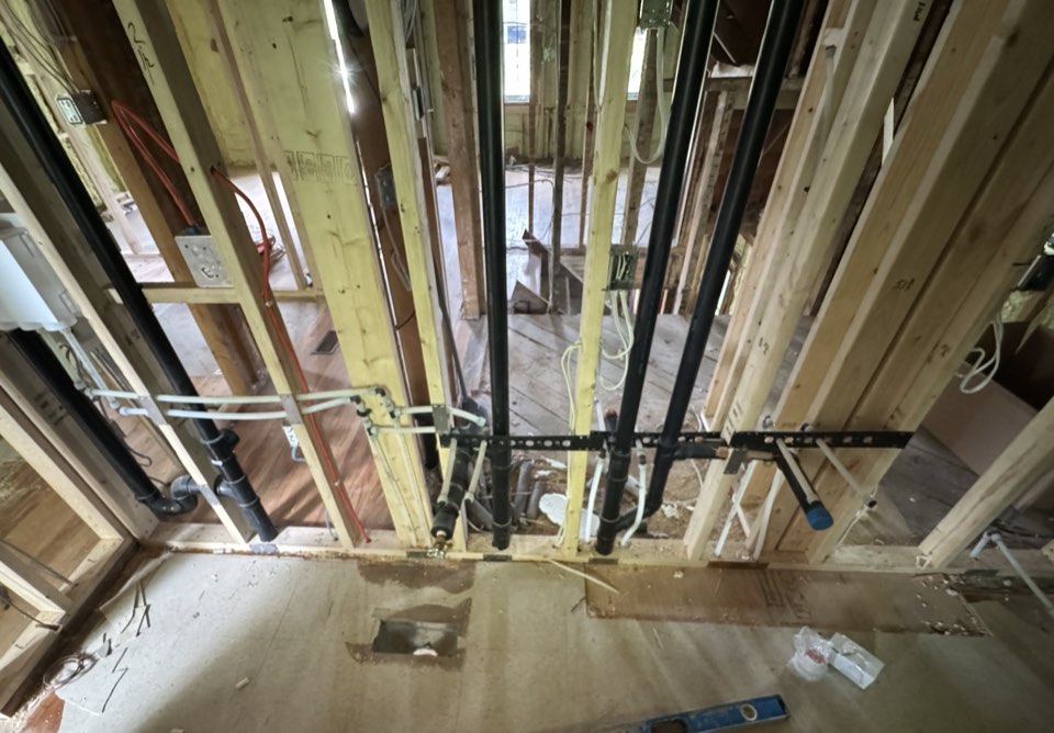 Plumbing rough-in: drain stacks and water lines through new wall framing