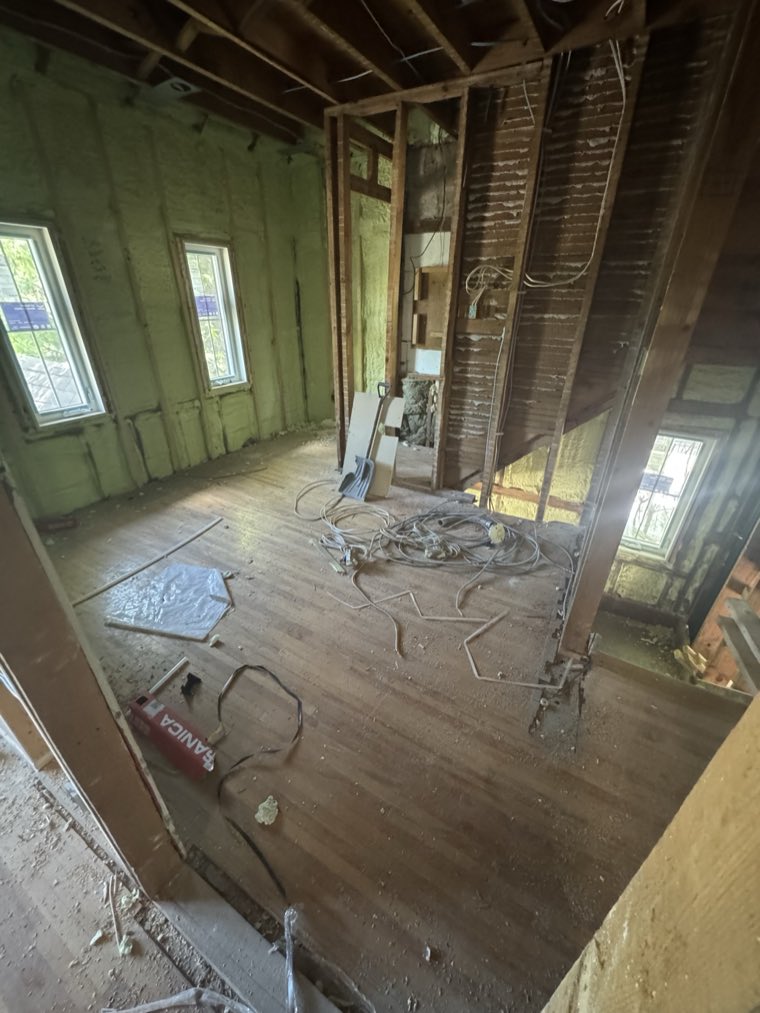 A gutted room with spray foam insulation and new wiring, ready for drywall